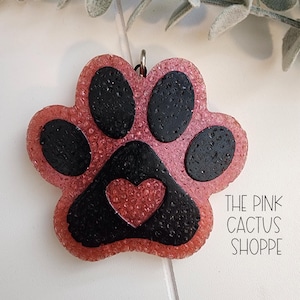 May include: Pink paw print charm with a black outline and a small red heart in the center. The charm is made of resin and has a glittery finish.