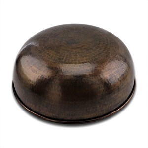 May include: A large, round, hammered copper bowl with a dark brown patina. The bowl has a slightly flared rim and a smooth, polished interior.