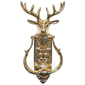 May include: A gold-toned deer head door knocker with intricate details. The knocker features a detailed deer head with antlers and a ring for knocking.