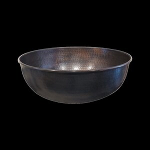 May include: A large, hammered copper bowl with a dark patina finish. The bowl is round and has a wide, shallow shape.