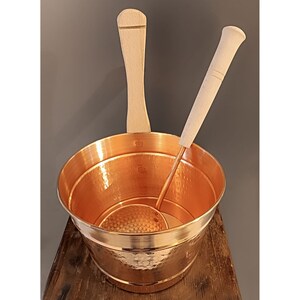 May include: A copper foot bath with a hammered finish and two wooden handles. The foot bath includes a copper ladle with a wooden handle.