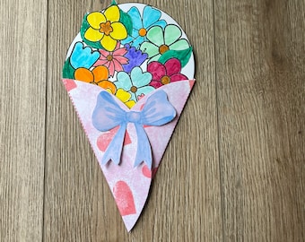 May include: A colourful paper craft bouquet of flowers in a pink cone-shaped envelope with a blue bow. The flowers are yellow, orange, red, pink, blue, and green.