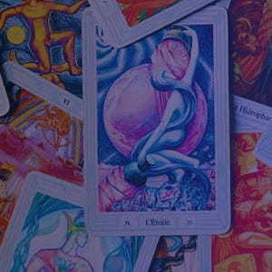 Peut inclure: Un ensemble de cartes de tarot avec diverses illustrations. La carte centrale représente une femme aux cheveux flottants devant une lune rose. D'autres cartes montrent des figures et des symboles, avec du texte en français et en anglais.