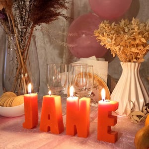 lit orange letters candles in decor. From letters the name Jane.