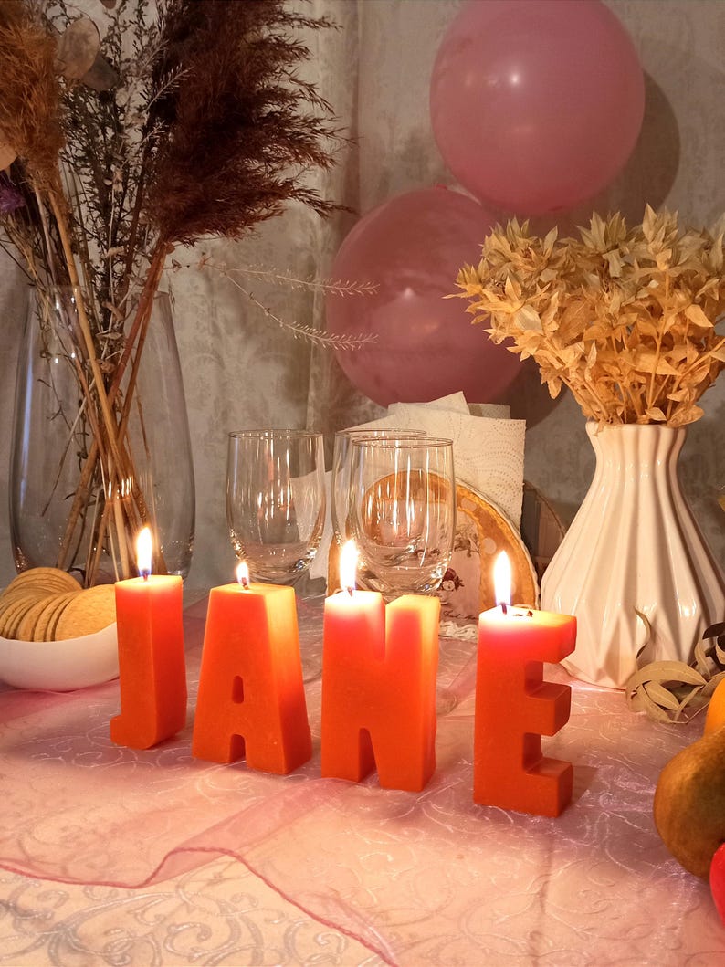 lit orange letters candles in decor. From letters the name Jane.