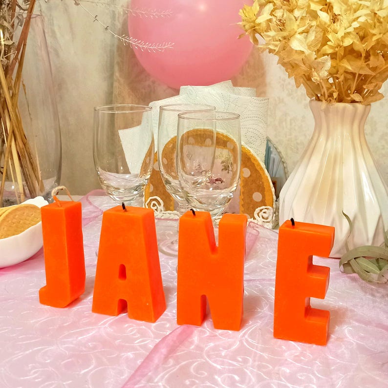Orange letters candles in the form of a word on the holiday table.