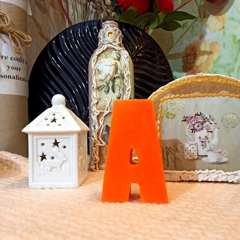 Front view of a large orange letter A candle.