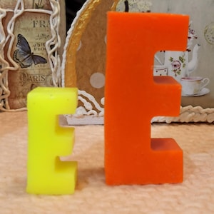 Size comparison of letter E candles in yellow and orange colors.