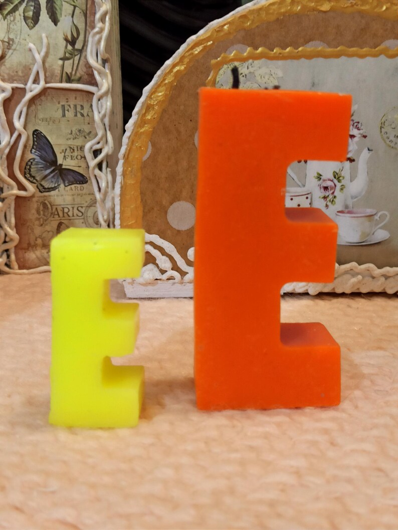 Size comparison of letter E candles in yellow and orange colors.