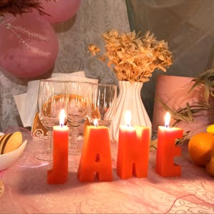lit orange letters candles in decor. From letters the name Jane.