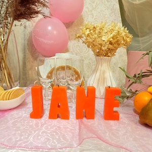 Orange letters candles in the form of a word on the holiday table.