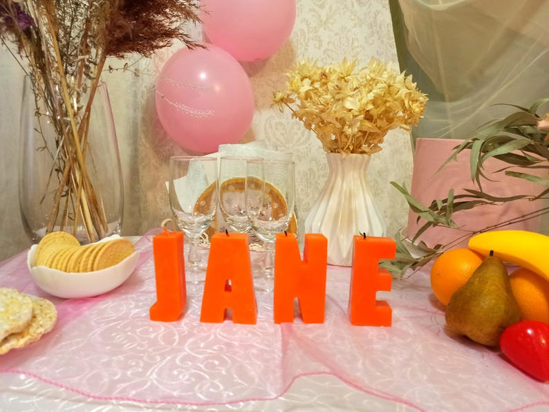 Orange letters candles in the form of a word on the holiday table.