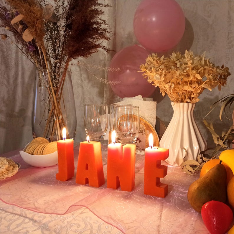 lit orange letters candles in decor. From letters the name Jane.
