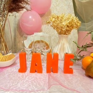 Orange letters candles in the form of a word on the holiday table.