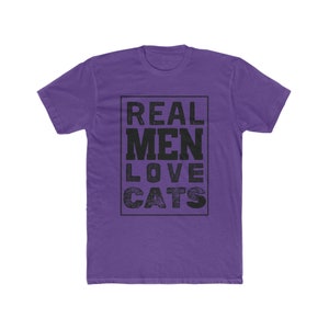 Könnte beinhalten: Lilafarbenes T-Shirt mit dem Text "REAL MEN LOVE CATS" in einem schwarzen Kasten.