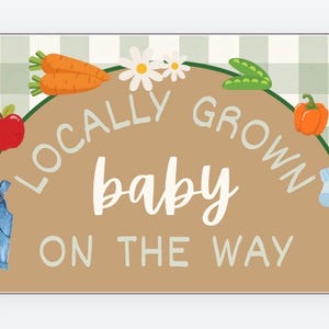 May include: A rectangular sign with a tan background and a green and white checkered border. The sign features illustrations of vegetables and the text "Locally Grown Baby On The Way."