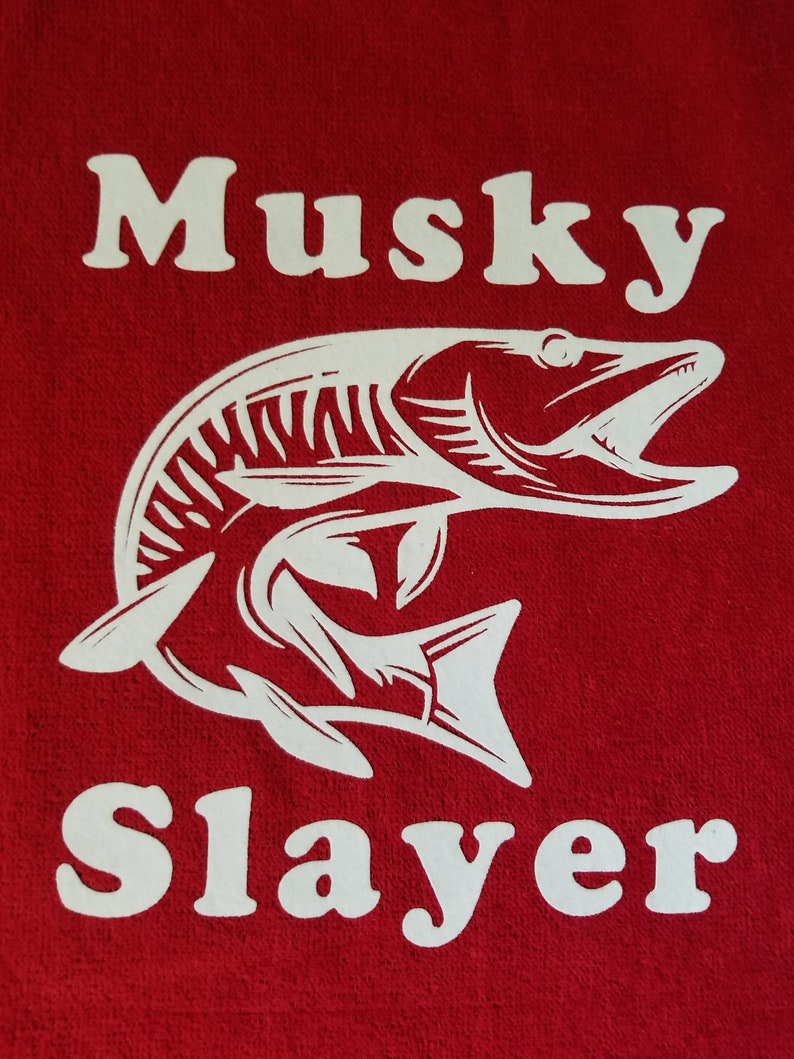以下が含まれることがあります： 赤い生地に「Musky Slayer」という白い文字と、魚の白いシルエットが描かれている。