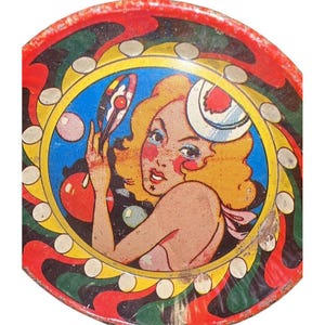 May include: Vintage, round metal tray with a pop art style illustration of a woman with blonde hair, holding a mirror. The tray has a red, yellow, green, and black swirl design around the central image. The woman is wearing a hat with a red and white design.