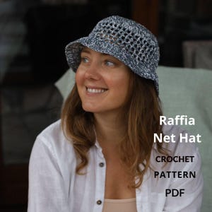 Puede incluir: Sombrero de red de rafia gris y blanco con ala y diseño calado de ganchillo. La imagen incluye el texto "Raffia Net Hat CROCHET PATTERN PDF". Un accesorio de moda.