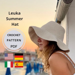 May include: A crochet pattern PDF for a summer hat, with the words "Leuka Summer Hat CROCHET PATTERN PDF" in white text on a grey circle. The pattern is available in English, German, Italian, and Spanish.