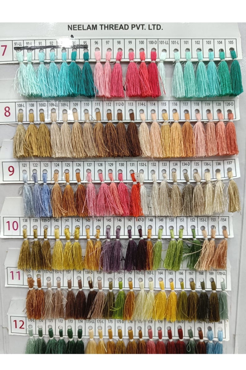 May include: A color chart of thread spools with tassels. The chart is labeled with numbers from 7 to 12 and includes numbers from 91 to 184. The chart is labeled "NEELAM THREAD PVT. LTD."