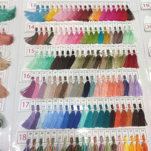 May include: A color chart of thread samples, with each color labeled with a number. The chart is divided into 18 rows, with each row containing 24 thread samples. The thread samples are arranged in a rainbow pattern, with the colors ranging from red to purple.
