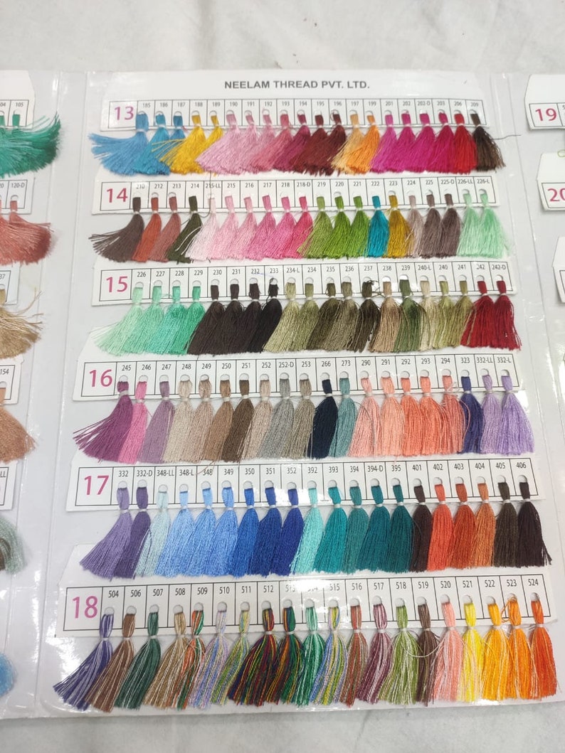 May include: A color chart of thread samples, with each color labeled with a number. The chart is divided into 18 rows, with each row containing 24 thread samples. The thread samples are arranged in a rainbow pattern, with the colors ranging from red to purple.