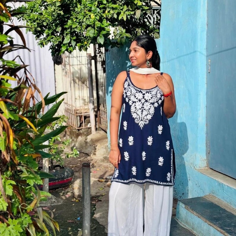 Navy blue cotton chikankari short top with white Lucknowi embroidery; sleeveless noodle-strap kurti paired with white cotton pants.