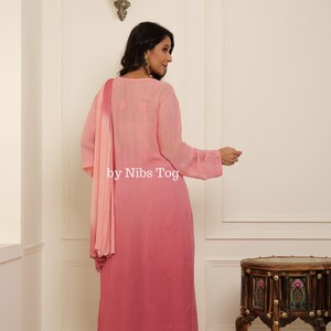 May include: A pink ombre kurta with embroidered details and a matching palazzo pant. The kurta has a round neckline and three-quarter sleeves. The palazzo pant has a lace trim at the bottom. The outfit is paired with a pink chiffon dupatta.