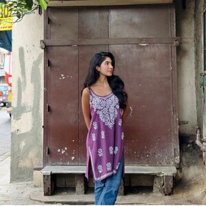 Purple cotton sleeveless kurti top, handmade with Lucknowi chikankari embroidery and noodle-straps, shown with blue jeans.