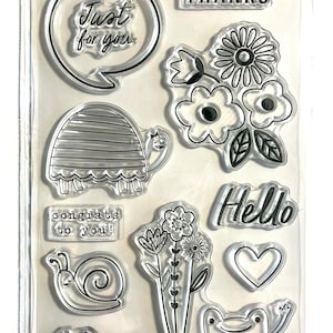 May include: A set of 11 clear stamps featuring various designs, including a turtle, a snail, a frog, flowers, and phrases like "Just for you", "Thanks", "Hello", and "Congrats to you!"