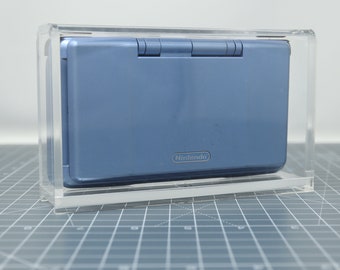 May include: A blue Nintendo DS handheld gaming console in a clear acrylic display case.