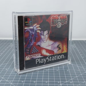 May include: A clear plastic case containing a PlayStation game. The game is Tekken 3, a fighting game for the PlayStation console. The game case is red and black with a picture of a character from the game on the front. The game is rated PAL.