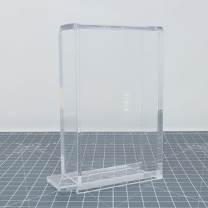 Pu&ograve; includere: Una teca espositiva in acrilico trasparente con forma rettangolare e base. La teca &egrave; progettata per proteggere e mettere in mostra oggetti.
