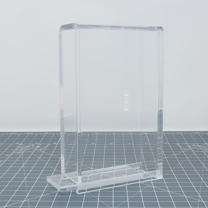 Pu&ograve; includere: Una teca espositiva in acrilico trasparente con forma rettangolare e base. La teca &egrave; progettata per proteggere e mettere in mostra oggetti.