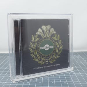 May include: A clear plastic CD case with a black CD inside. The CD features a gold and green design with the text "Songs for the Front Row" and "Ocean Colour Scene". The text "The Best of Ocean Colour Scene" is printed at the bottom of the CD.