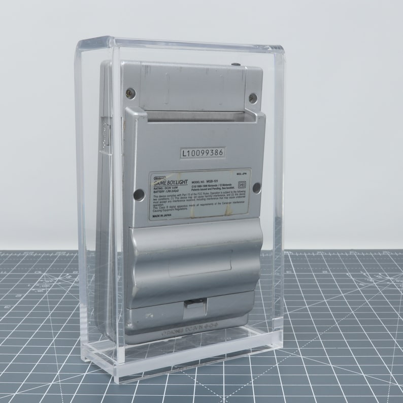 Pu&ograve; includere: Una console per videogiochi portatile Game Boy Light argentata in una teca di acrilico trasparente. Sul retro della console &egrave; presente un'etichetta con il testo "GAME BOY LIGHT" e il numero di modello "MGB-101". Il numero di serie "L10099386" &egrave; stampato sull'etichetta.