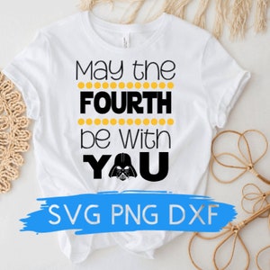 Puede incluir: Camiseta blanca con texto negro que dice "Que la fuerza te acompañe" con un gráfico de Darth Vader. El texto está rodeado de puntos amarillos. La parte inferior de la camiseta tiene una pancarta azul con el texto "SVG PNG DXF".