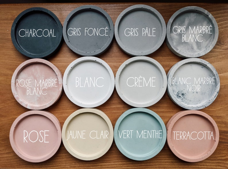 Puede incluir: Doce posavasos redondos de hormig&oacute;n en varios colores y patrones, incluyendo carb&oacute;n, gris, blanco, crema, rosa, amarillo, verde y terracota. Los posavasos est&aacute;n etiquetados con sus nombres de colores en franc&eacute;s.