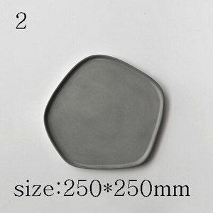 Puede incluir: Una bandeja de servir de hormig&oacute;n gris de forma irregular con bordes redondeados. La bandeja mide 250 mm por 250 mm.