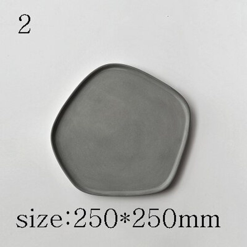 Puede incluir: Una bandeja de servir de hormig&oacute;n gris de forma irregular con bordes redondeados. La bandeja mide 250 mm por 250 mm.