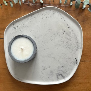 Puede incluir: Una bandeja de cer&aacute;mica blanca con un dise&ntilde;o gris moteado. Un peque&ntilde;o portavelas gris con una vela blanca est&aacute; en la bandeja.
