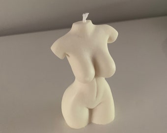 May include: A white candle shaped like a human torso. The candle has a single wick.