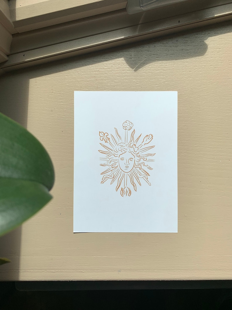 K&ouml;nnte beinhalten: Eine Linienzeichnung einer Sonne mit einem Gesicht, umgeben von stilisierten Blumen und Bl&auml;ttern. Die Zeichnung ist in Gold auf wei&szlig;em Hintergrund.