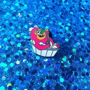 May include: A red monster with a green nose is taking a bath in a white bathtub. The monster is holding a yellow guitar and has a happy expression on its face. The bathtub is filled with white bubbles.