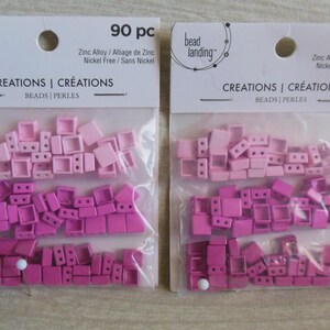 May include: Two packages of 90 pink and white square beads. The beads are in three shades of pink, with the lightest shade on top and the darkest shade on the bottom. The packages are labeled "bead landing" and "CREATIONS | CRÉATIONS BEADS | PERLES".