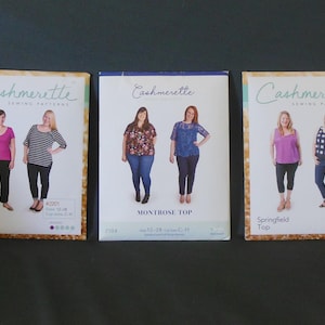 May include: Three sewing pattern packages from Cashmerette. The packages feature images of women wearing the finished garments. The patterns are for a Concord T-Shirt, Montrose Top, and Springfield Top.