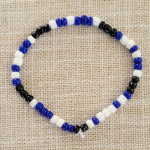 Pu&ograve; includere: Un braccialetto con perline alternate nere, bianche e blu.