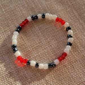 May include: A beaded bracelet with alternating black, white and red beads.