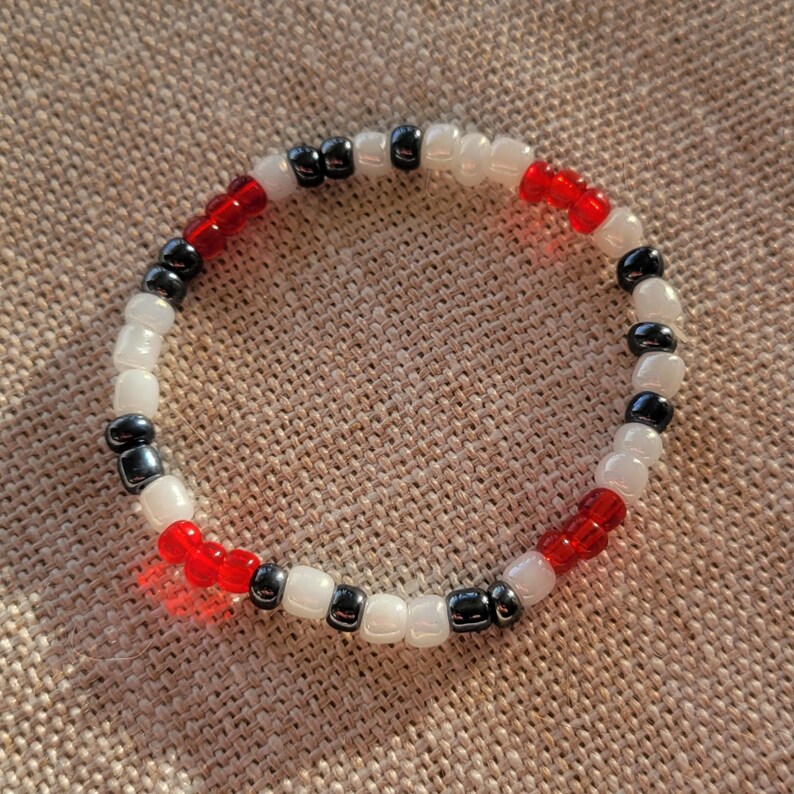 May include: A beaded bracelet with alternating black, white and red beads.
